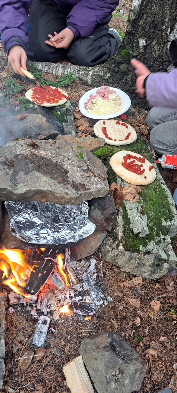 en gruppe mennesker som sitter rundt et bål med mat på
