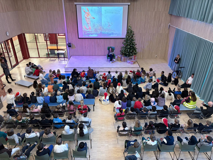 en gruppe mennesker som sitter i et rom med en stor skjerm